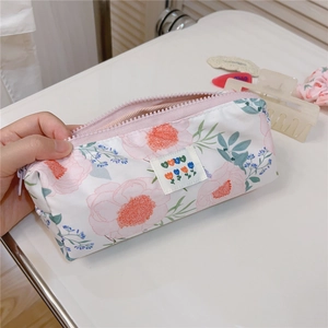 Close-up of pink floral pencil case with white fabric label and pink zipper on a desk
