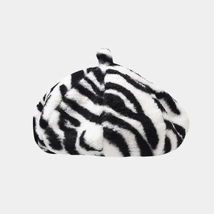 Détail du béret en peluche à motif zèbre avec un pompon en fausse fourrure sur le dessus