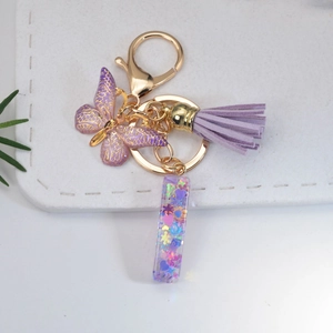 Close-up of purple butterfly keychain with tassel and sequin-filled acrylic charm