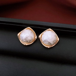 Macro shot of gold-plated wrinkled texture earrings with white cotton pearl inlay