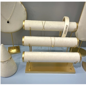 Close-up of beige velvet jewelry display stands with gold metal accents for bracelets