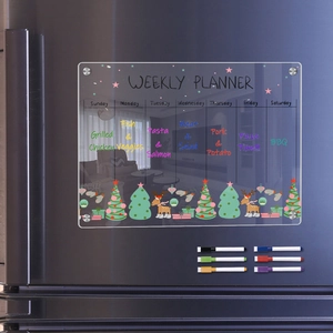 Macro view of magnetic acrylic weekly planner with festive Christmas icons on a black fridge