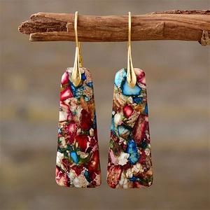 Detail of bohemian drop earrings with colorful mosaic stone textures on wood branch