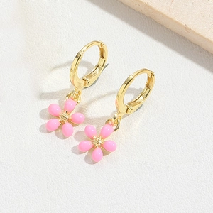Detailed macro view of pink enamel flower charms on golden hoops with soft lighting