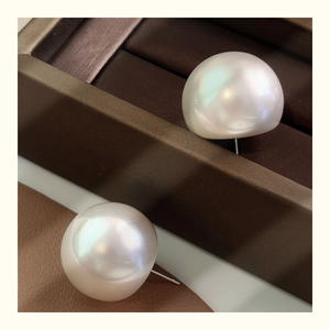Detailed close-up of large round pearl earrings with iridescent luster on leather base
