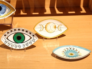 Ceramic eye-shaped jewelry trays featuring green, blue, and gold lunar patterns