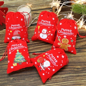 Lot de cinq sacs cadeaux de Noël en velours rouge sur table en bois avec lumières