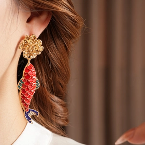 Detail of vintage gold flower and red enamel koi fish earrings worn by a model