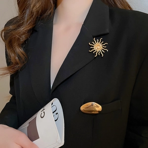 Detail of a golden sunflower brooch with a radiant sunburst design on a black blazer