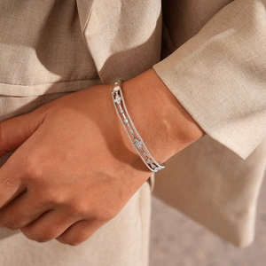 Detail of silver hollowed double row bracelet with micro-pave zircon flower on woman wrist