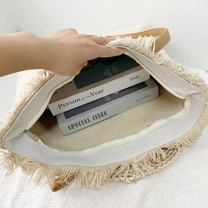Detailed view of the large interior capacity of this beige canvas tote bag with tassels