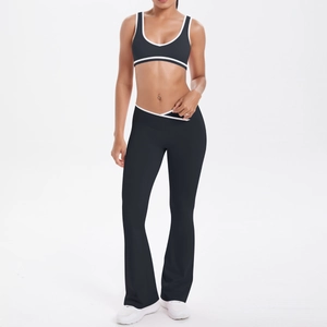 Detail of high-waisted flared yoga pants and black sports bra with white piping trim