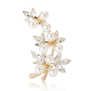 Elegant gold flower brooch with white pearls and crystals on a reflective white background