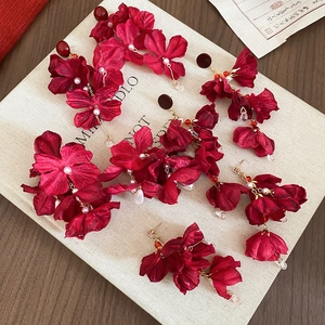 Detailansicht der Vintage-Ohrringe mit roten Blumen, Quasten und Perlen auf Buch