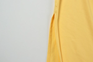 Detail der hochwertigen Seitenschlitznähte an einem leuchtend gelben eleganten Kleid