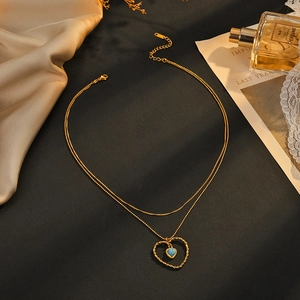 Collier double rang en acier inoxydable doré avec cœur et gemme bleue sur fond noir