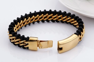 Detail of black rubber woven bracelet featuring a polished gold buckle on white background