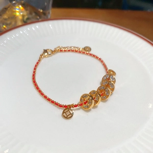 Détail macro d'un bracelet tissé rouge avec pièces dorées et strass blancs scintillants