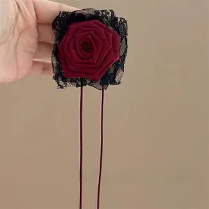 Detailed view of a dark red vintage rose hair tie with black lace and long ribbons