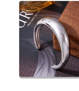 Detail of minimalist polished silver cuff bracelet with thick curved open design