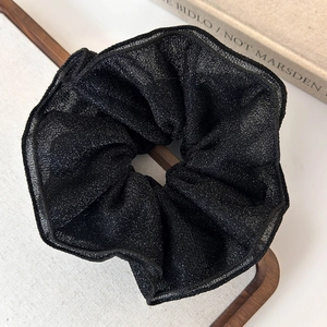 Close-up of elegant black shimmery mesh hair scrunchie with layered ruffle pleats