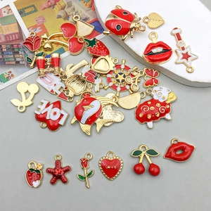 Close-up of golden alloy red enamel charms featuring heart and fruit shapes for DIY jewelry