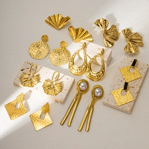 Detailed close-up of various vintage-style 18K gold earrings on natural stone props