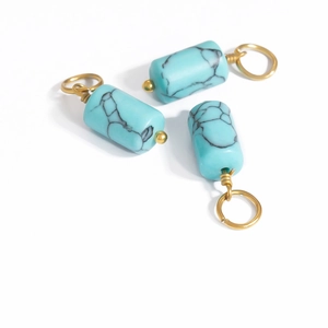 Detailed macro view of three turquoise barrel pendants with gold stainless steel wire coils