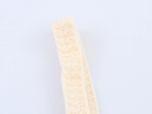 Close-up detail of beige crochet knit fabric showing intricate cable knit patterns and texture