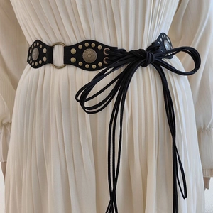 Detail of vintage Y2K black lace-up belt with metal rivets and circular badges
