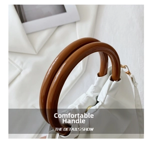 Detail of elegant white pleated leather handbag with smooth resin ring handle and gold clasp