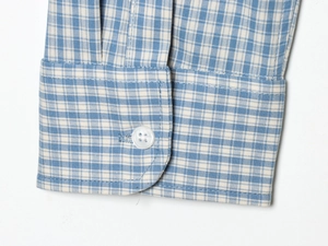 Macro detail of blue and white plaid shirt cuff with precise stitching and white button