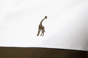 Macro shot of giraffe embroidery on a two-tone polo shirt made of pique cotton fabric