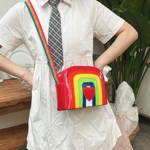 Detailed close-up of rainbow crossbody bag featuring heart motif and striped woven strap