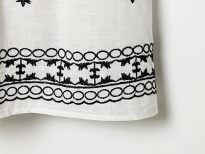 Close-up of white dress showing black floral embroidery and puff sleeve fabric texture