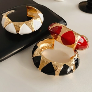 Macro view of wide geometric cuff bangles with white, red, and black enamel finishes