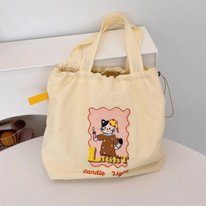 Detail of cream canvas tote bag featuring cute cat print and drawstring closure
