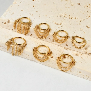 Golden stainless steel nose rings with multi-layer chains on beige stone texture