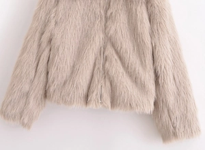 Detail of light khaki faux fur texture and smooth zipper on a short plush coat