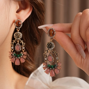 Detail of vintage style earrings with floral metal, rhinestones and pink waterdrop beads