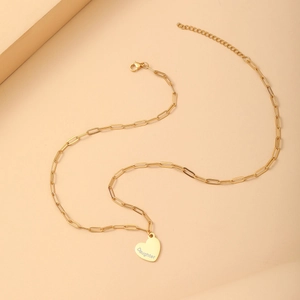 Close-up of gold paperclip chain necklace with heart pendant engraved with Daughter