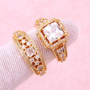 Detail of gold-plated rings with micro-set square and round zircon stones on a pink background