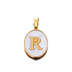 Detailed macro view of an oval gold pendant with white mother of pearl and a raised letter R