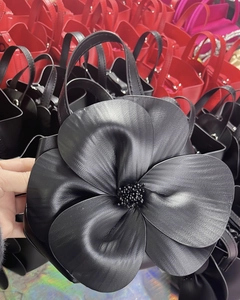 Detail of the 3D leather flower design and textured finish on a black tote handbag