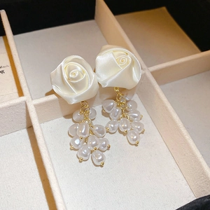 Macro detail of silk rose earrings with dangling clusters of irregular cream pearls