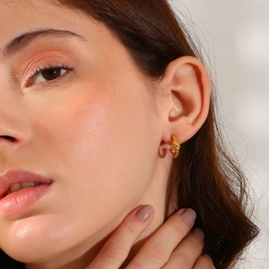 Detail of twisted 18K gold plated stainless steel hoop earring on a model
