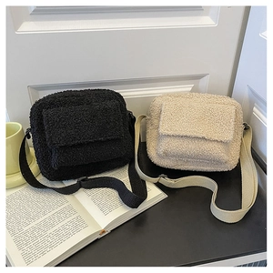 Detail view of black and beige fuzzy fleece crossbody bags with adjustable straps