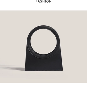 Detail of minimalist black geometric handbag with unique oversized round ring handle