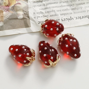Top view of four red resin strawberry charms with white pearls and gold metal leaves