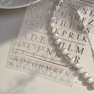 Vista macro di adesivi per unghie con lettere in oro rosa e texture metallica lucida